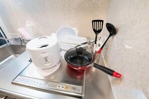 A kitchen area with a coffee maker, a red pot, and kitchen utensils on a stainless steel countertop. - Ferio Kamata II (Tokyo)