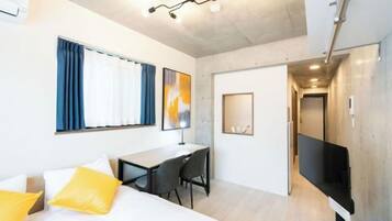 Quarto de hotel moderno com cama, escrivaninha e televisão.