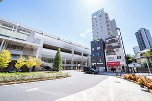 A multi-story building with a parking garage, a pedestrian walkway, and a street with vehicles.