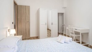 A hotel room with a bed, a desk, and a wardrobe. - Profumo di Caruggi - Room Porto Antico (Genova)