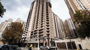A high-rise building with multiple balconies, surrounded by other tall buildings and trees. - Rodos Arcadia Apartments (Odesa)