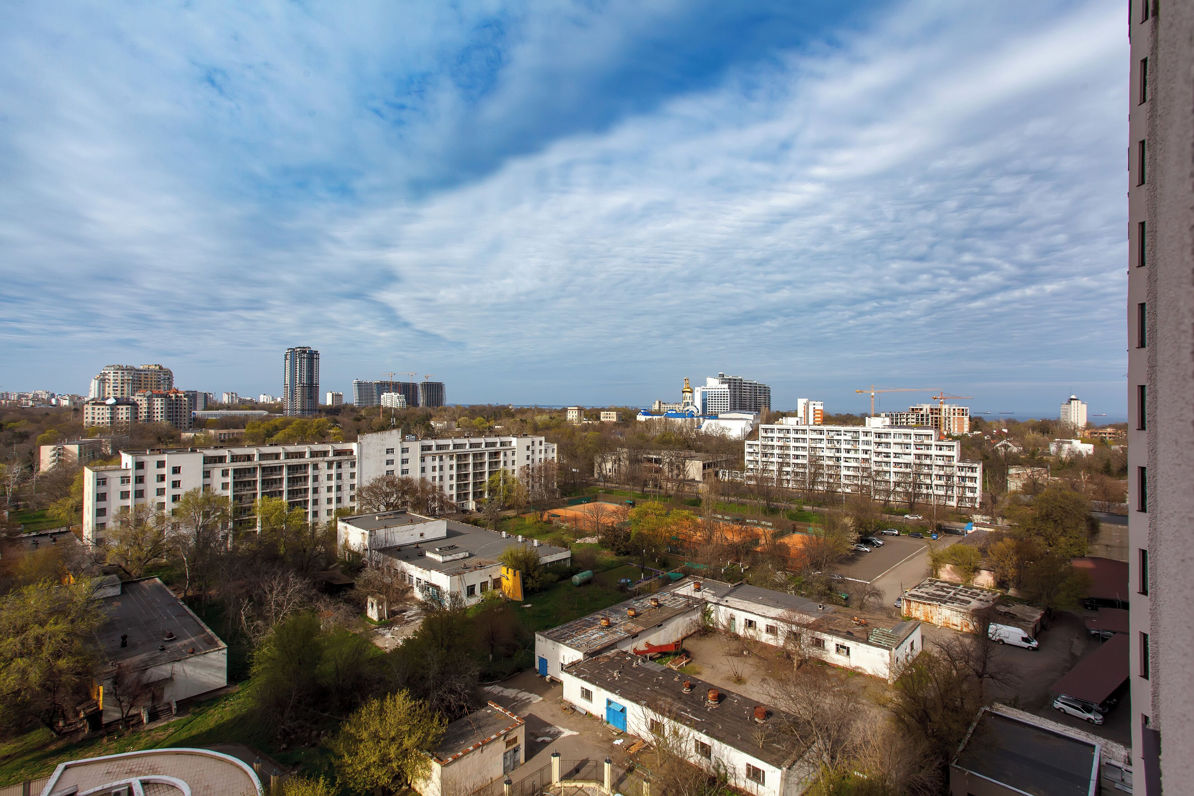 A high-rise building with multiple floors, a parking lot, and surrounding buildings.