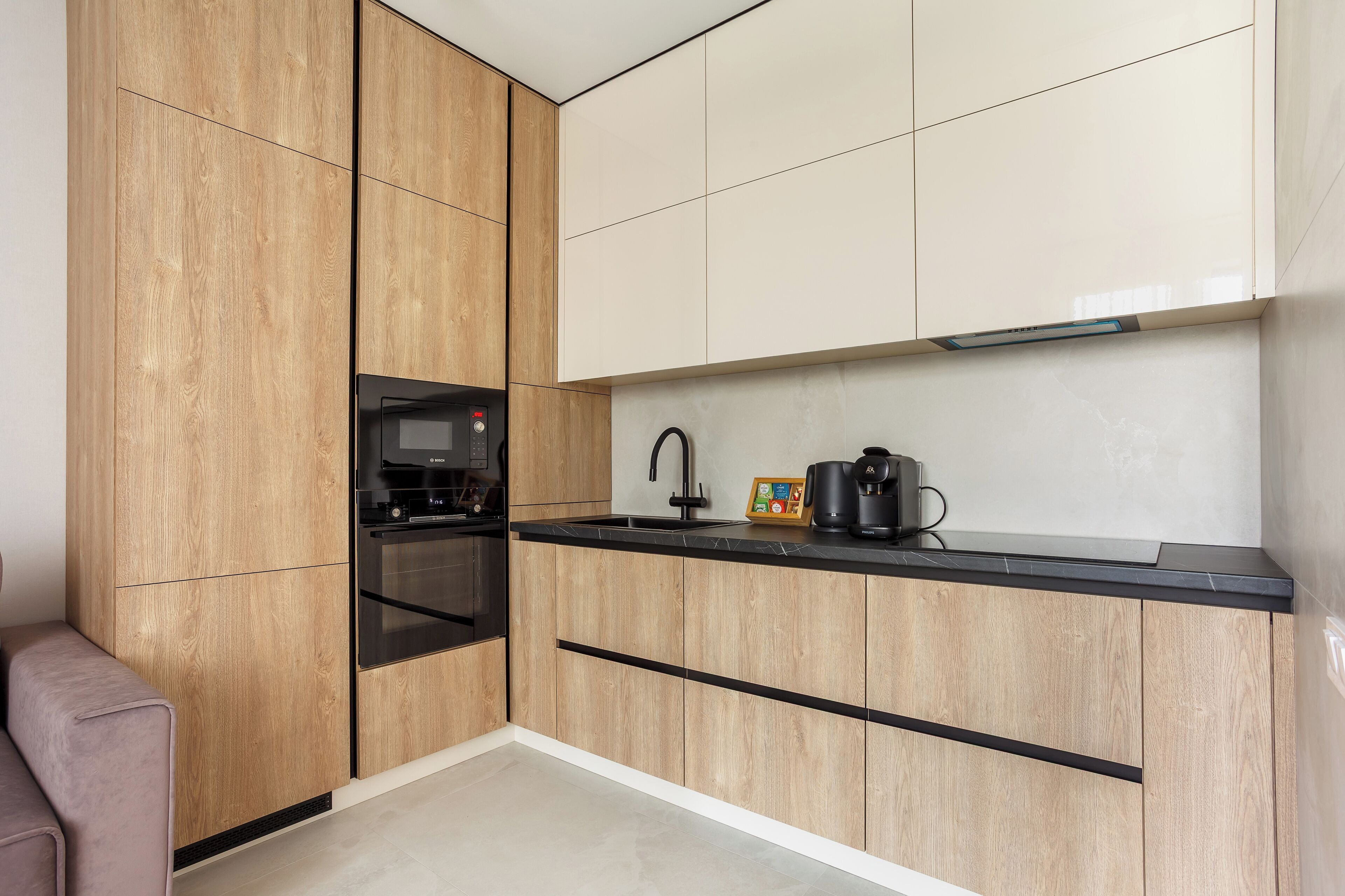 A modern kitchen with wooden cabinetry, a built-in oven, and a coffee maker on the countertop.