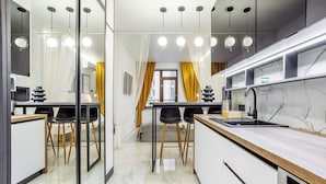 A modern kitchen with a marble countertop, black chairs, and pendant lighting. - Rodos Arcadia Apartments (Odesa)