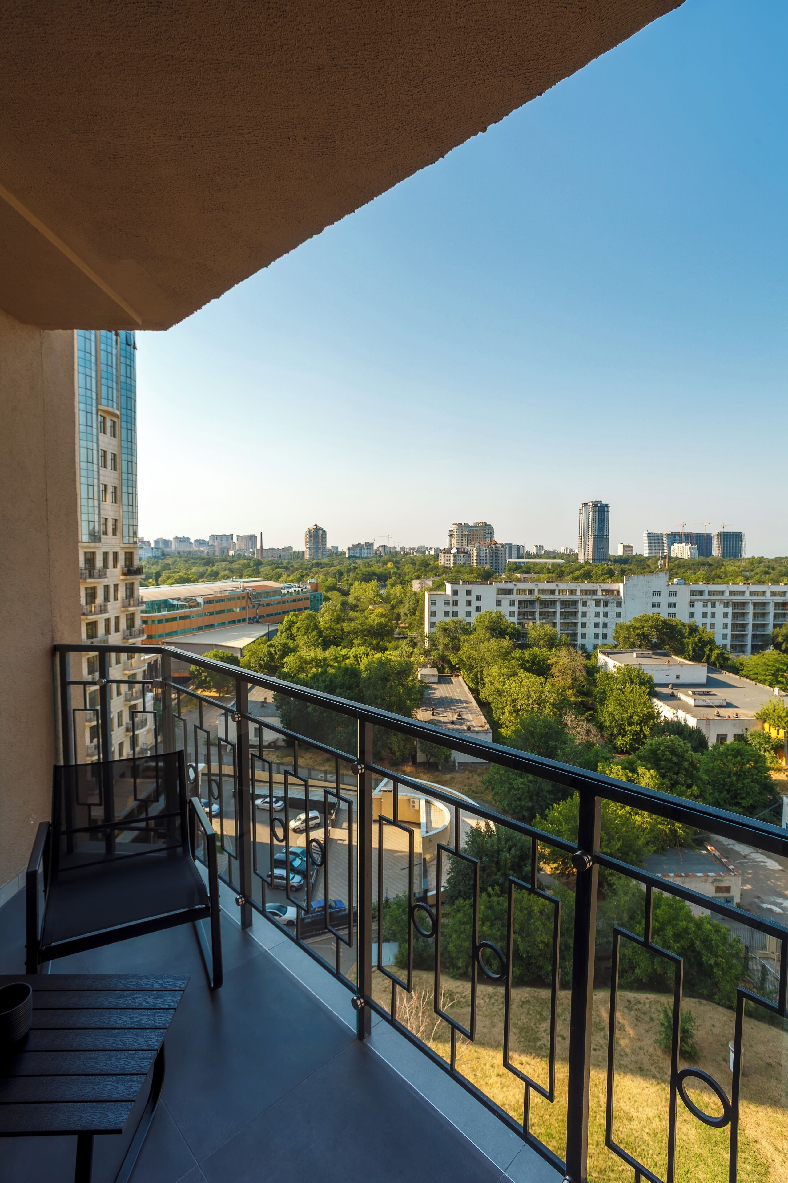 Un balcón con vistas a un paisaje urbano, con edificios y zonas verdes.