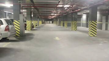 An indoor parking garage with multiple levels, concrete pillars, and directional arrows on the floor.