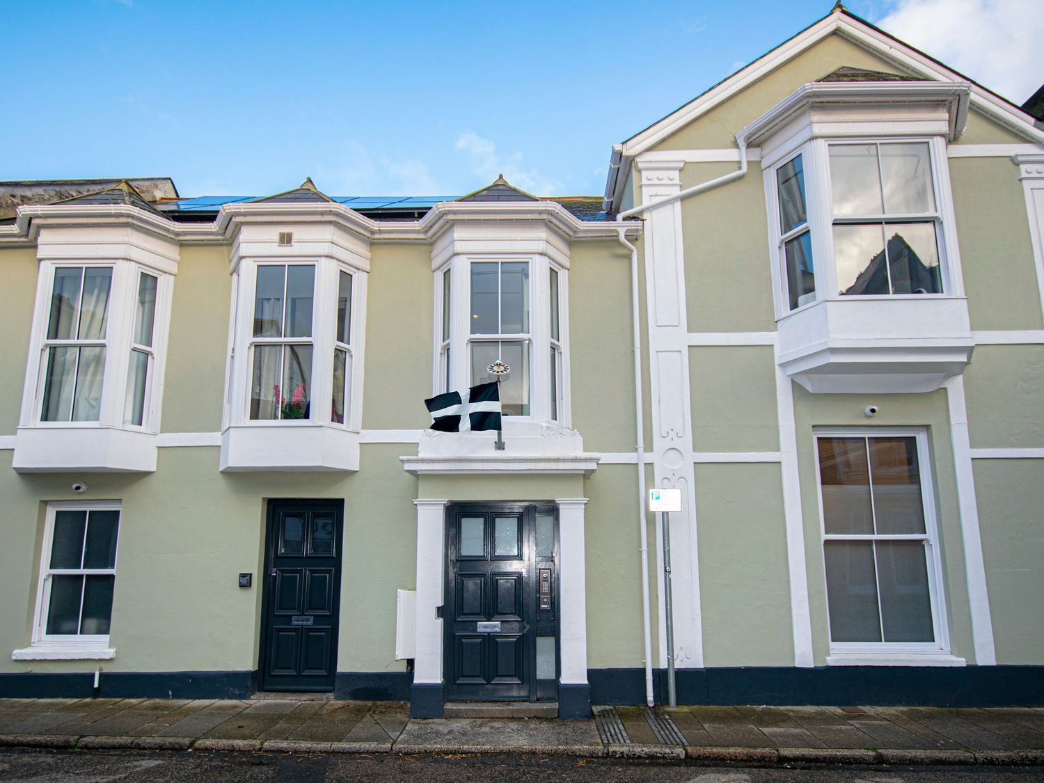 A row of terraced houses with bay windows and a central entrance.