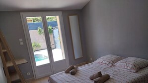 A bedroom with a bed, a wooden ladder, a sliding door, and a pool view.