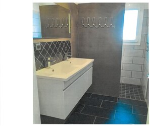 Une salle de bain avec un lavabo blanc, un miroir et un porte-serviettes.