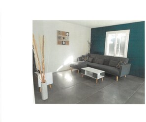 Un salon moderne avec un canapé gris, une table basse blanche et un mur d’accent bleu.