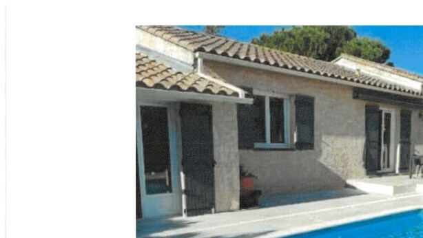 A building with a swimming pool, a covered patio, and a stone facade.