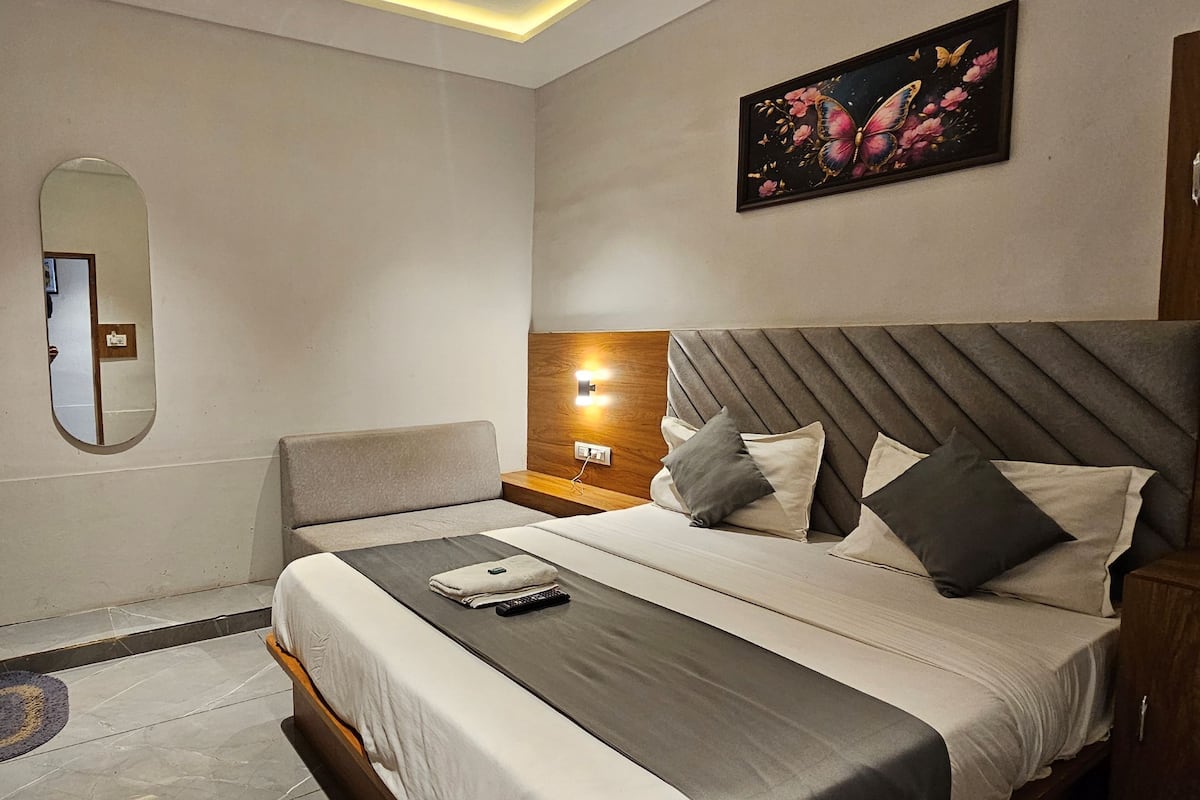 A modern hotel room with a bed, bedside table, nightstand, and a TV mounted on the wall.