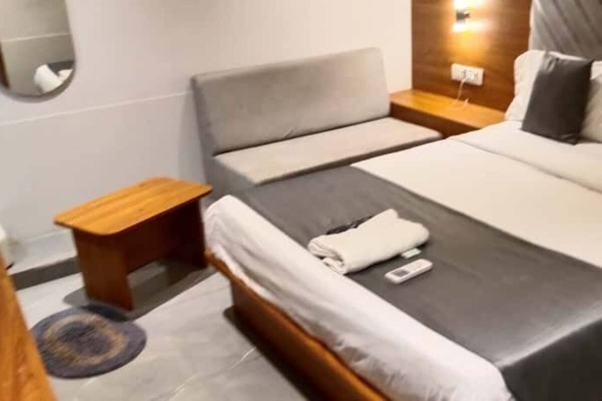 A hotel room with a double bed, a bedside table, a nightstand, and a mirror on the wall.