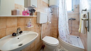 Ein Badezimmer mit Waschbecken, Toilette, Dusche und Toilettenpapierhalter.