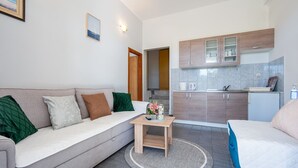 Ein kompakter Wohnraum mit einer Couch, einem kleinen Tisch, einer Küchenzeile und einem Bett.