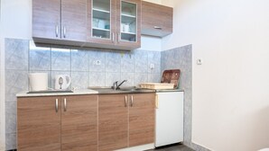 Eine kompakte Küche mit Holzausstattung, einem eingebauten Backofen und einem kleinen Kühlschrank.