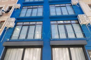 A building with multiple air conditioning units, large windows with curtains, and a blue facade. - TaksimBlue (Istanbul)