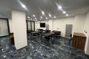 A conference room with a marble floor, multiple tables, chairs, a wooden podium, and a mounted TV on the wall. - TaksimBlue (Istanbul)