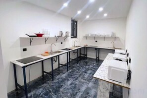 A compact kitchen with a central island, built-in appliances, and a black marble floor. - TaksimBlue (Istanbul)