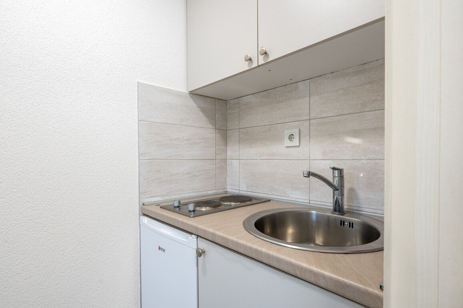 Een koelkast, een kookplaat, kookgerei, borden en bestek