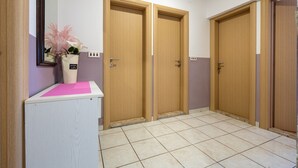 A hallway with two wooden doors, a white counter with a pink mat, and a vase with flowers.