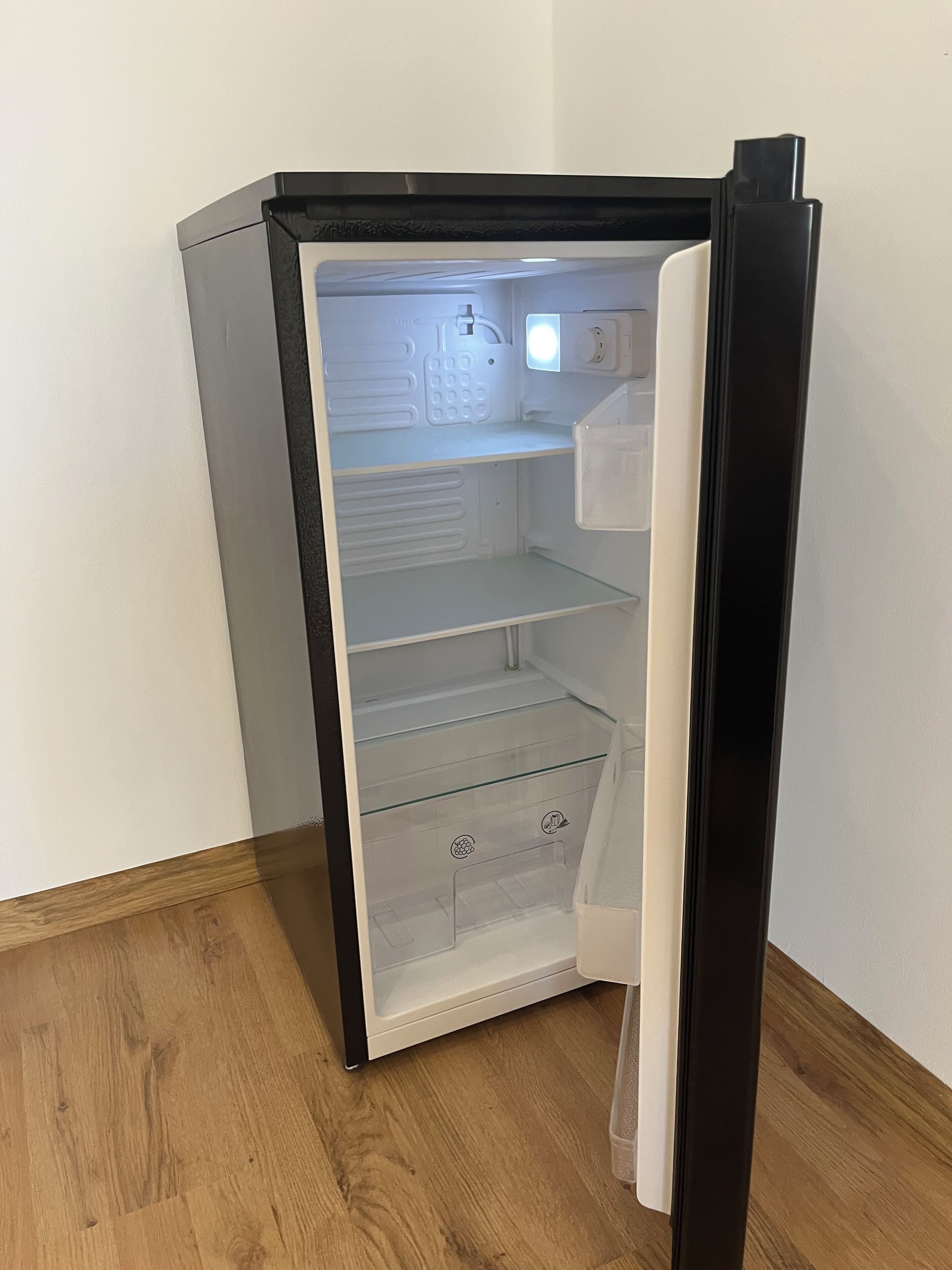 A small, black refrigerator with a freezer compartment on top and a main compartment below.