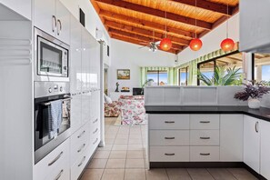 A modern kitchen with white cabinetry, a built-in oven, and a ceiling fan.