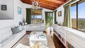 Un salon moderne avec un plafond en bois, un lustre, un canapé, une table basse et une bibliothèque.