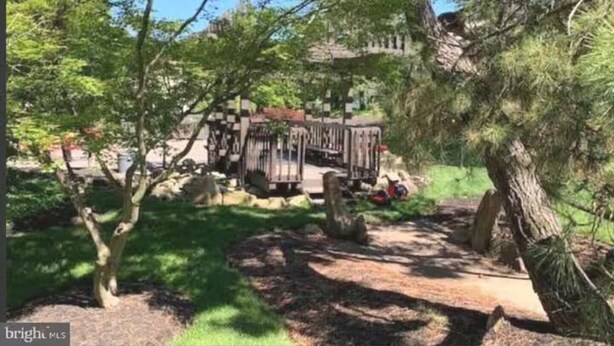 A park with a wooden bridge, trees, and a building in the background. - Full apartment, 7 minutes from dulles airport (Herndon)
