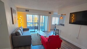 A modern living room with a grey sofa, a red armchair, and a TV mounted on the wall. - Full apartment, 7 minutes from dulles airport (Herndon)