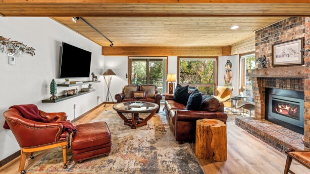 A cozy living room with leather furniture, a fireplace, and a large TV mounted on the wall.