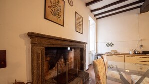 Una sala de estar acogedora con chimenea, un comedor con mesa de vidrio y una cocina al fondo.
