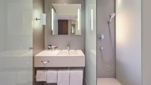Ein modernes Badezimmer mit Duschkabine aus Glas, großem Spiegel und weißem Waschtisch.