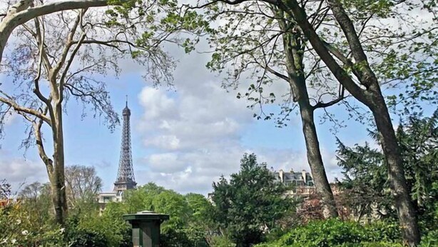 Ein Park mit Blick auf den Eiffelturm, Bänken und üppigem Grün.