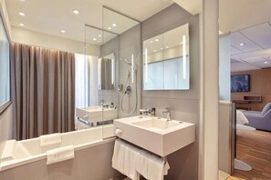 Ein modernes Badezimmer mit einer Badewanne, zwei Waschbecken, einem großen Spiegel und einer Dusche.