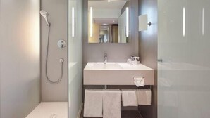 Ein modernes Badezimmer mit Dusche, Waschbecken und Spiegel.