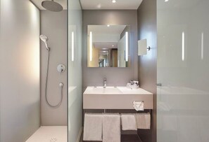 Ein modernes Badezimmer mit Dusche, Waschbecken und Spiegel.