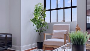 Een moderne woonkamer met een groot raam, een potplant, een bank en een salontafel.