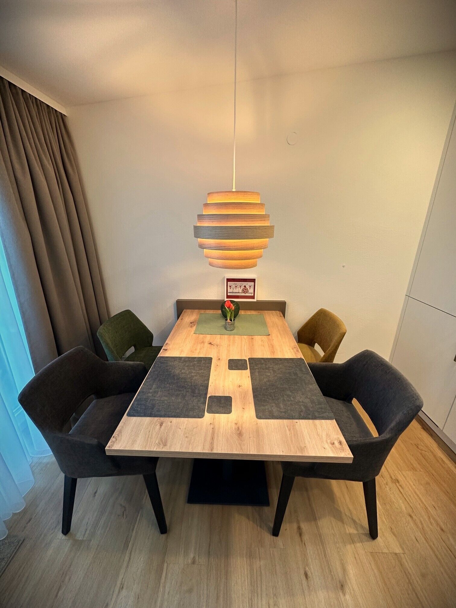 Ein Essbereich mit Holztisch, vier Stühlen und einer hängenden Pendelleuchte.