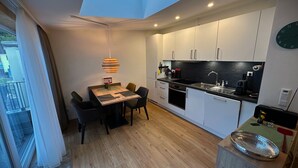 A modern kitchen with white cabinets, a black countertop, and a skylight above the dining area. - Apartment Bergblick | Top vacation apartment with view of mountains and Ahr 1-4 persons (Altenahr)