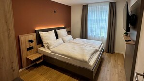 A modern hotel room with a large bed, wooden flooring, a desk, and a TV mounted on the wall. - Apartment Bergblick | Top vacation apartment with view of mountains and Ahr 1-4 persons (Altenahr)