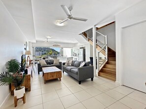 A spacious living room with a sofa, coffee table, and a view of the outdoors. - Beachside 17 (Nelly Bay)