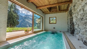 A spa area with a hot tub, wooden deck, and a view of mountains.