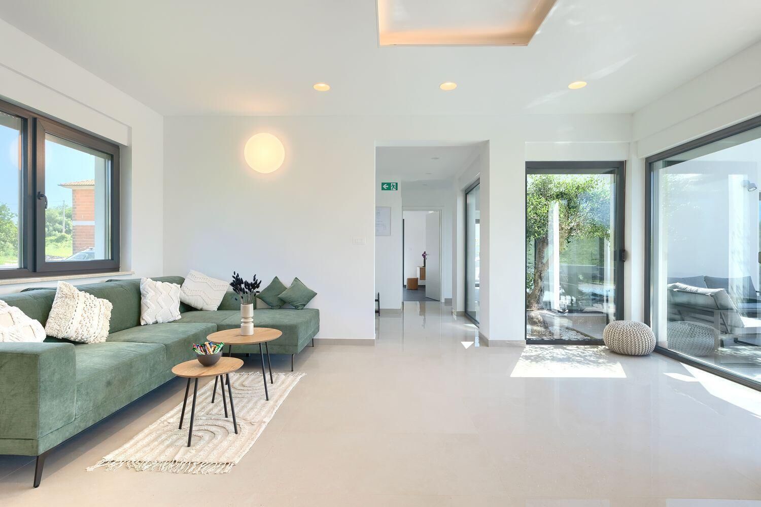 A modern, well-lit lobby with a green sofa, a small round table, and a glass partition.