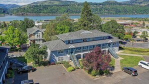 A multi-story building with a blue exterior, a central staircase, and a parking area with several cars. - The Hood River Condominiums (Hood River)