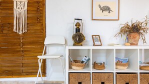 A white chair, a macrame wall hanging, a framed turtle illustration, a brass globe, a potted plant, and wicker baskets on a white shelf. - Casa en las Montañas de Benicassim — Mountain Forest Retreat with Private Terrace and Wi-Fi (Benicassim)