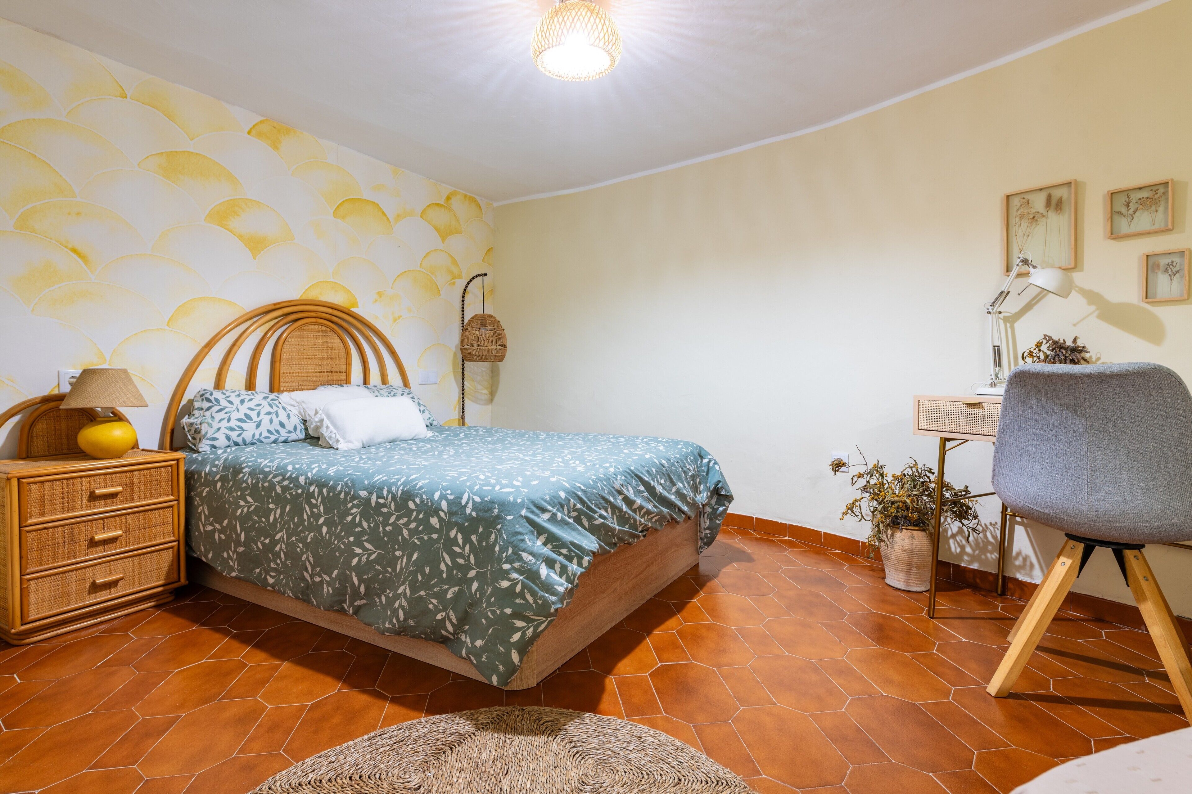 Un dormitorio con una cama, una mesita de noche, un escritorio, una silla y una pared con un diseño ondulado.