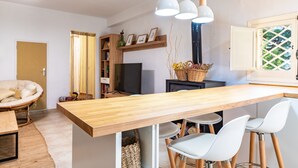 A modern kitchen with a wooden countertop, white chairs, pendant lights, and a television. - Casa en las Montañas de Benicassim — Mountain Forest Retreat with Private Terrace and Wi-Fi (Benicassim)
