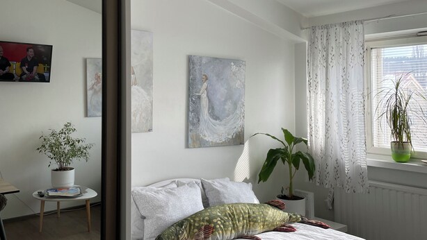 Ein modernes Schlafzimmer mit einem Bett, einer Topfpflanze und Kunstwerken an den Wänden.