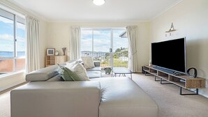 Una sala de estar moderna con un sofá grande, un televisor de pantalla plana y un balcón con vistas a la ciudad.